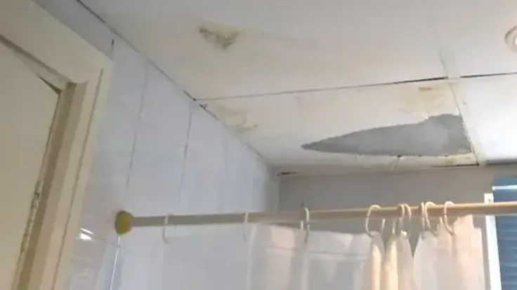 A water-damaged bathroom ceiling above the shower